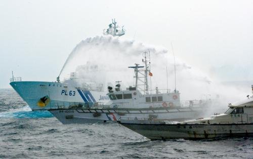 臺灣“海巡署”的巡邏船（中）在掩護保釣船“全家?！碧枺ㄓ遥┒惚苋毡竞Ｉ媳０矎d巡視船的水炮攻擊。