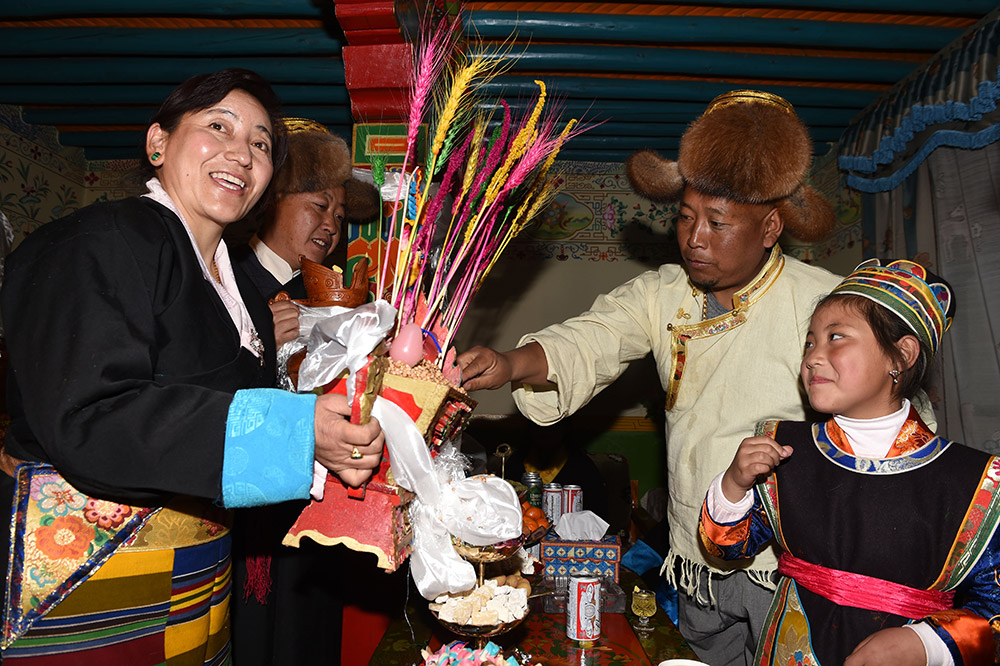 2月27日，拉薩市城關(guān)區(qū)阿壩林卡社區(qū)居民央拉（左）向鄰居敬獻(xiàn)“切瑪”。